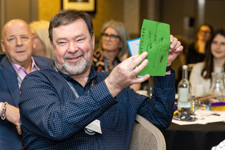 GS100223_Inform_3113 Inform trainer Geoff presenting a creative activity during Inform Together. He holds a drawing of a unicorn.