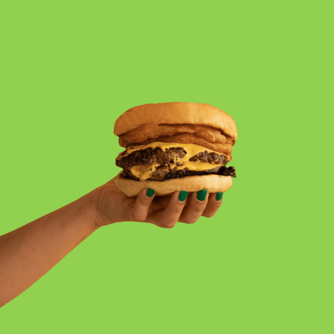 Change management burger recipe 3 – Equip A hand holding a burger on a green background