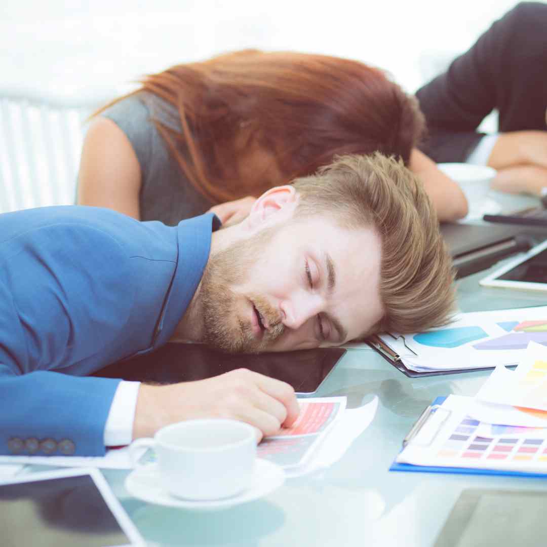 how-to-fix-unproductive-meetings A man falling asleep at his desk during a very dull meeting
