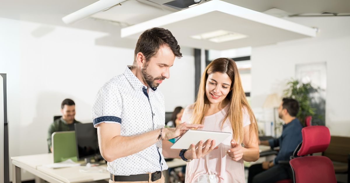 what-is-digital-fluency-featured A woman showing her colleague how to use a tablet