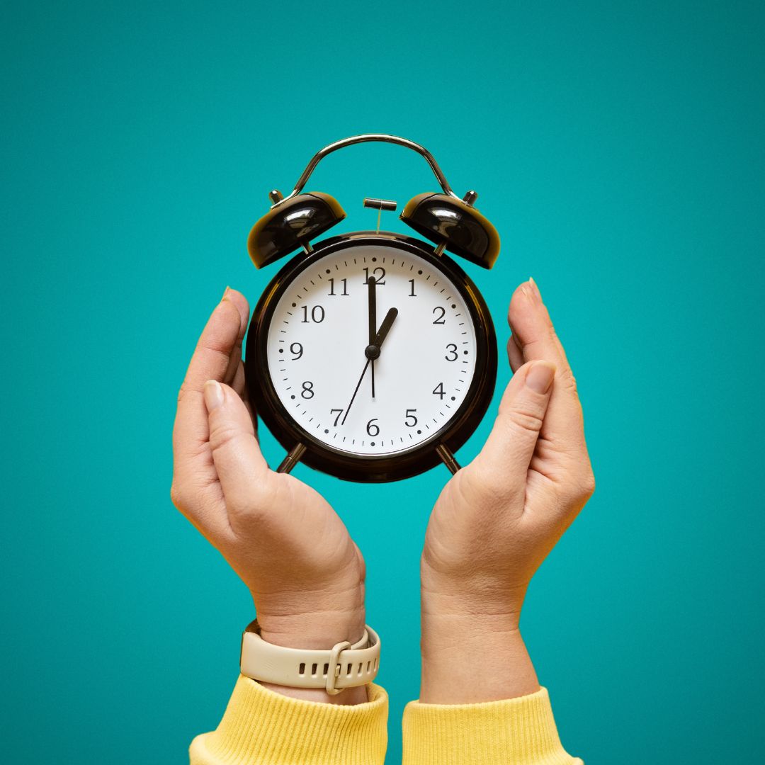 copilot-saves-time Top down view of a woman's hands, holding an analogue alarm clock