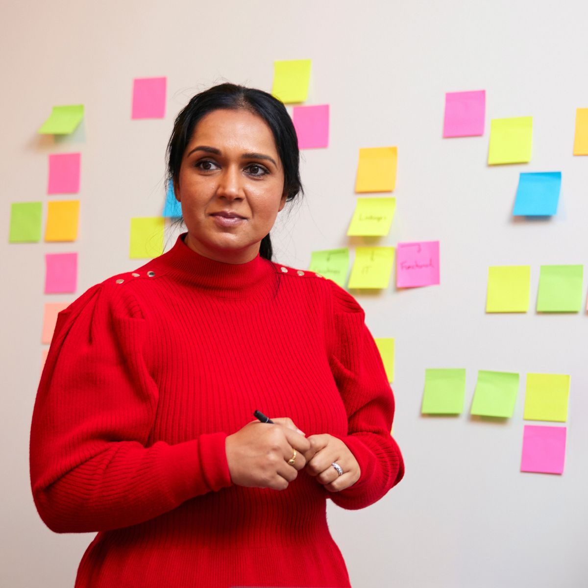 An Inform change manager listens to ideas in front of a wall of post-it notes